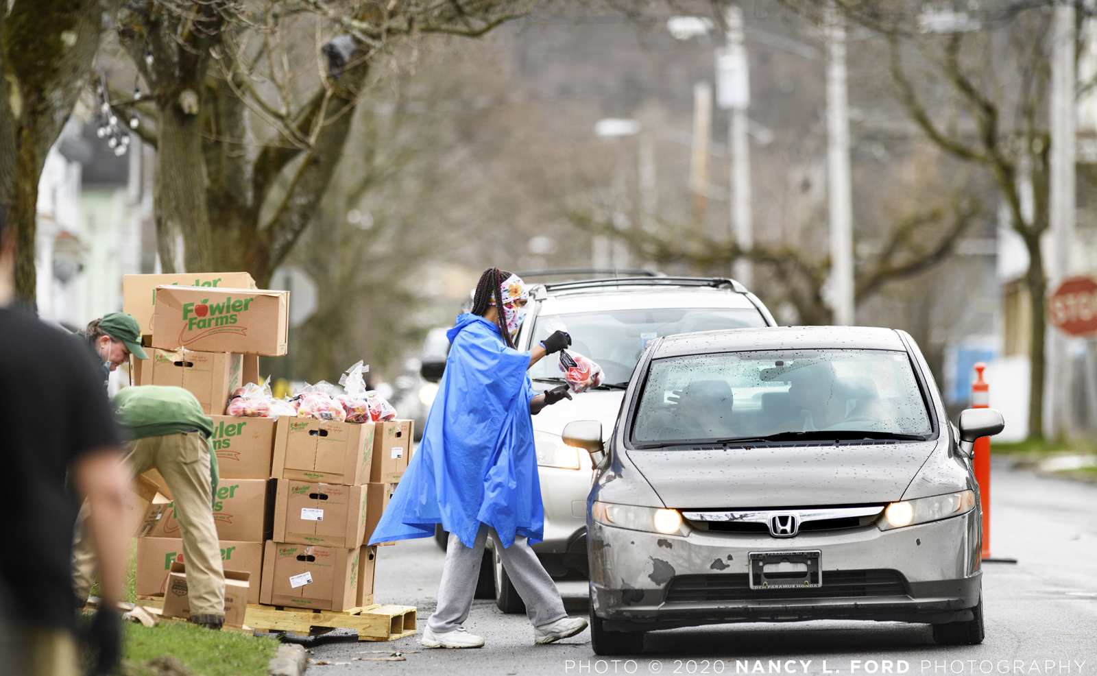 Motorists line up to receive food from the Johnson Park Center Drive-Thru Food Giveaway for the Disadvantaged on Monday, April 13, 2020 in Utica, NY. Employees of AVC Auctions volunteered their time to help give out the food.   (Copyright © 2020 Nancy L. Ford Photography)